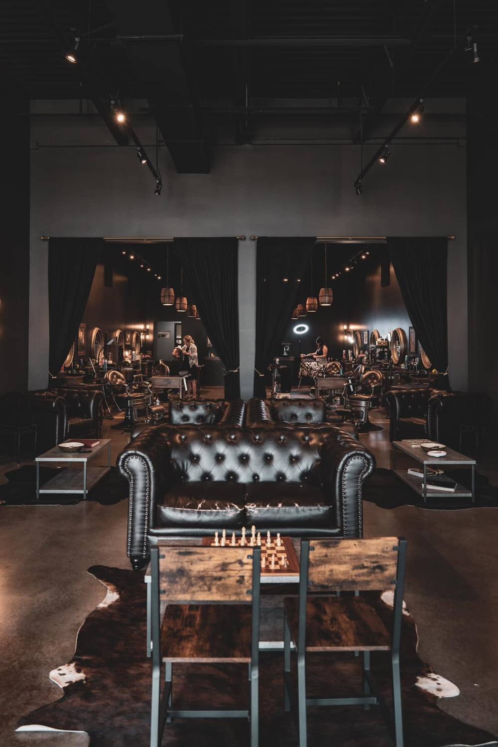 Wide view of The Cave lounge — leather chairs, walnut and low light